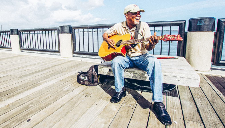A local playing music on a boardwalk in Charleston, SC